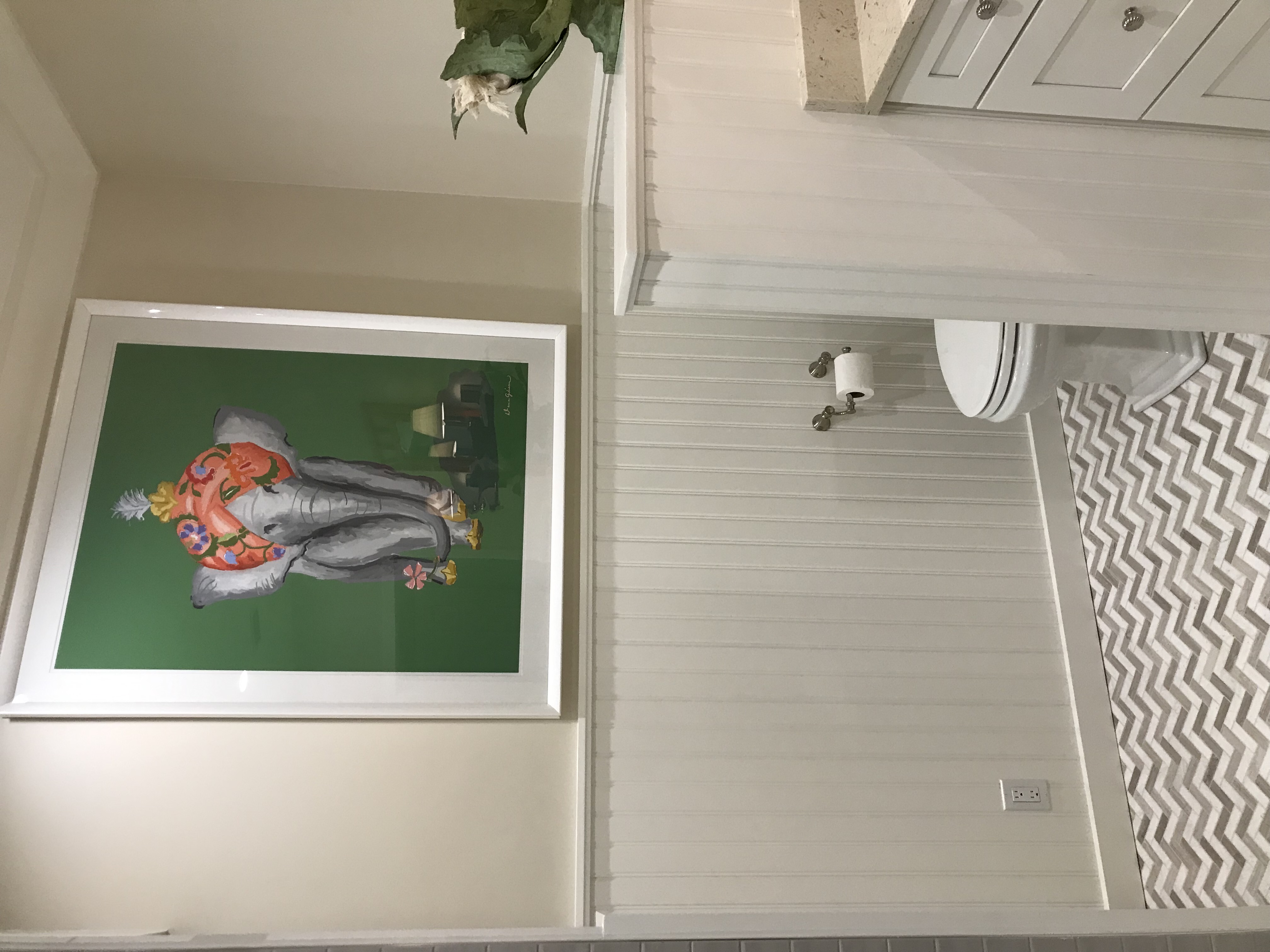 Beadboard millwork, patterned stone floor, and colorful framed artwork