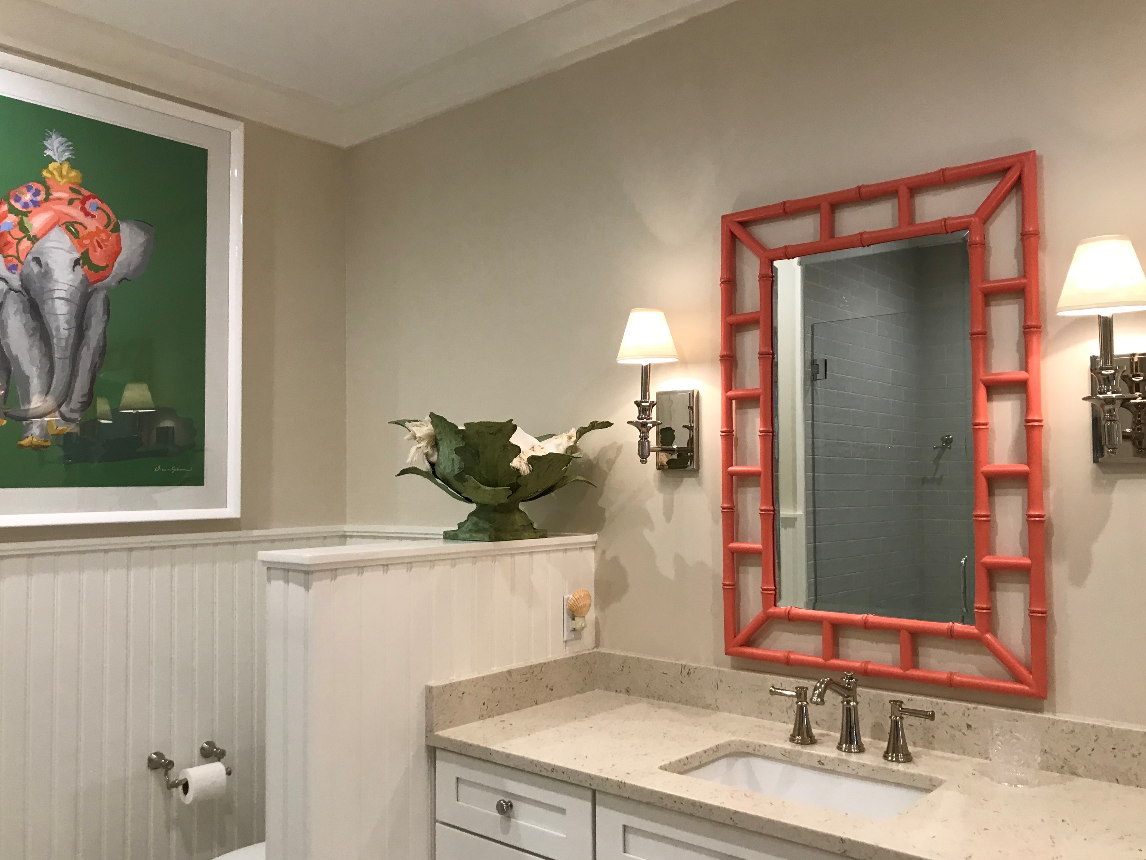 Coral bamboo-style mirror, custom vanity, beadboard, and framed artwork