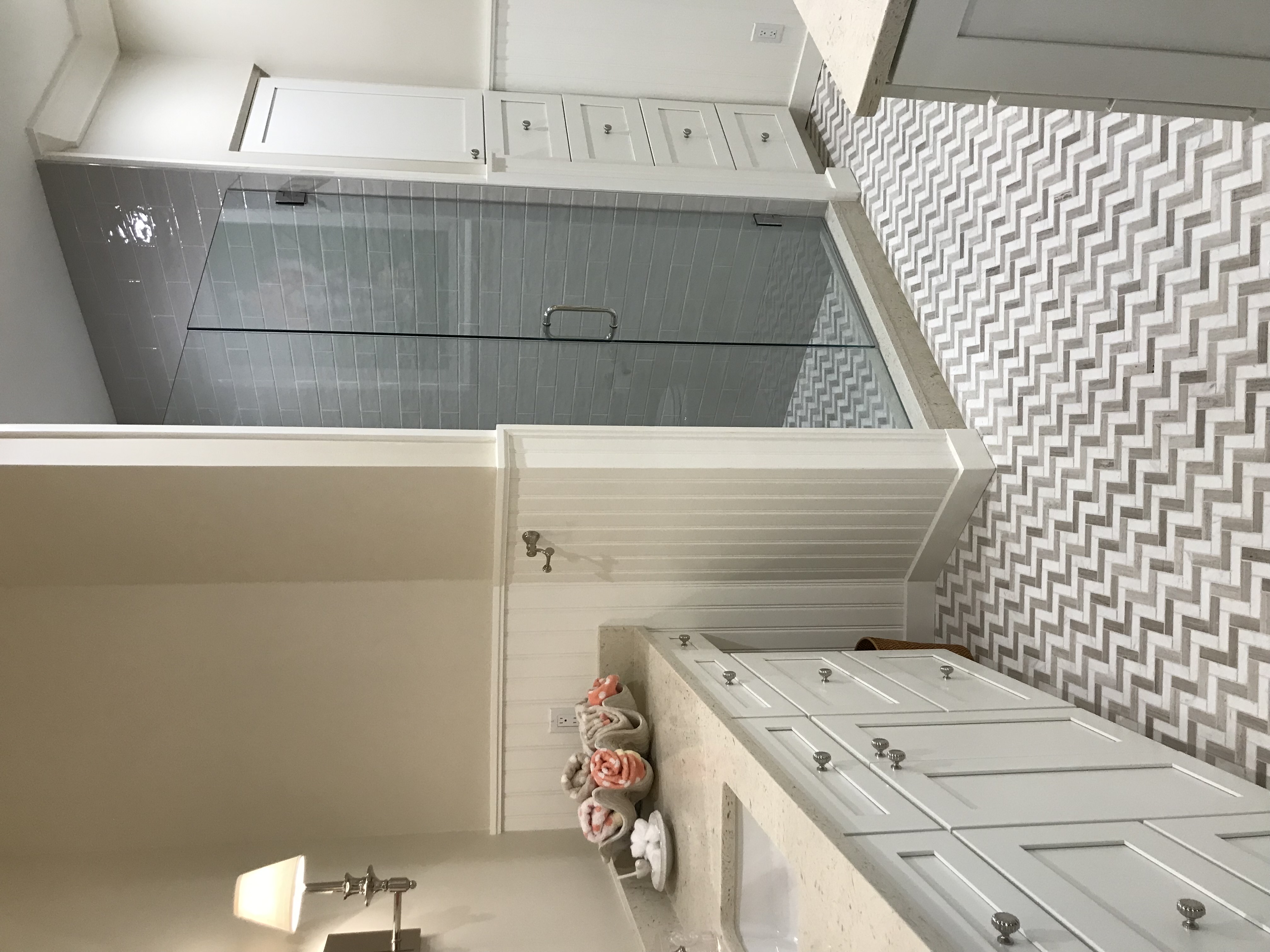 Completed coastal bathroom with custom cabinetry and glass shower