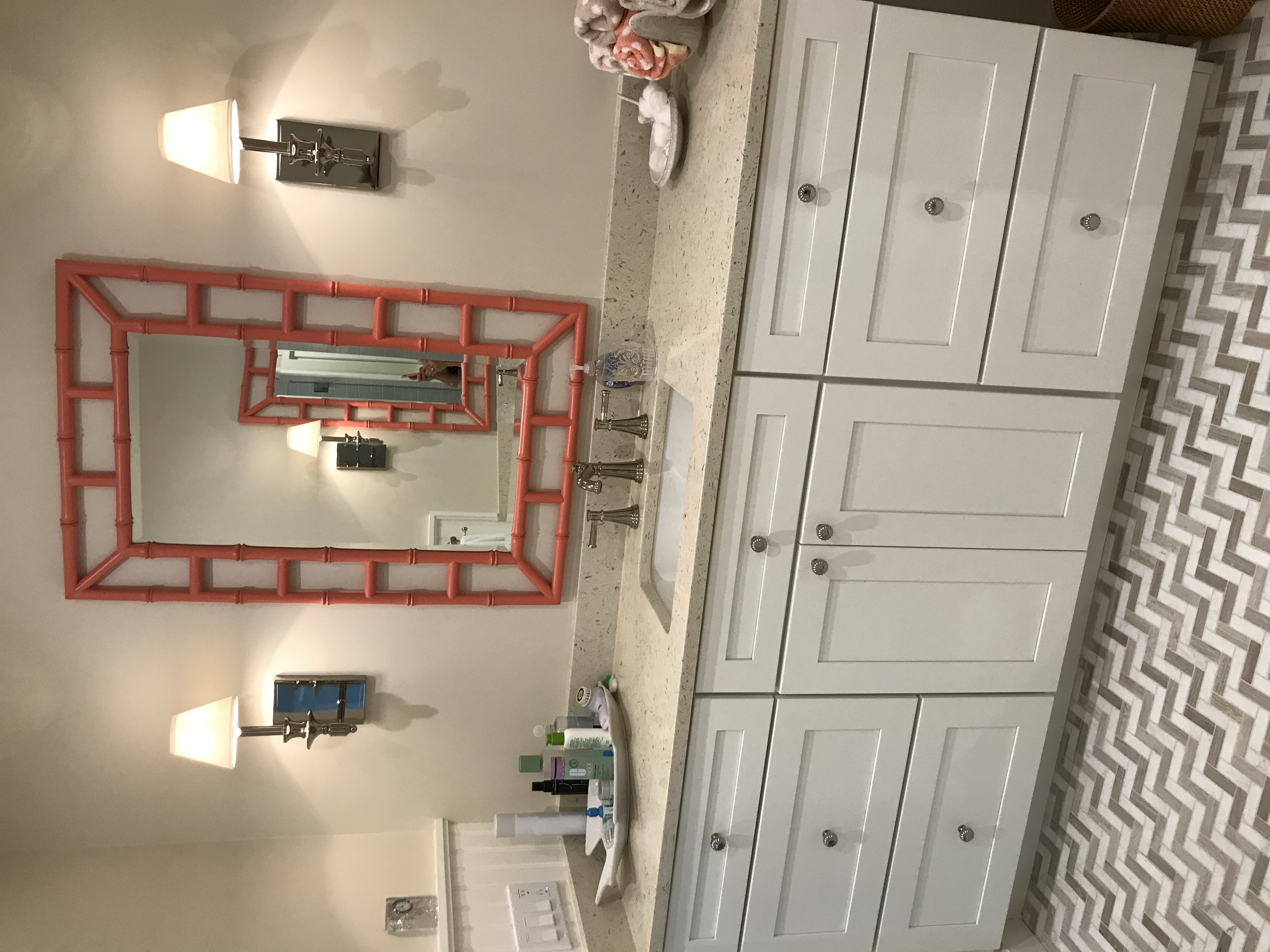 White custom bathroom vanity with coral mirror and polished wall sconces